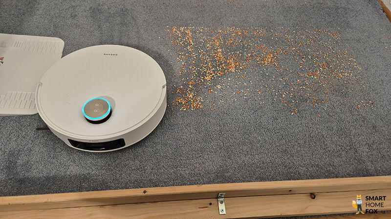 Der Dreame L50 Pro Ultra saugt Schmutz auf einem Teppichboden, mit wenig aufgenommenem Sand.